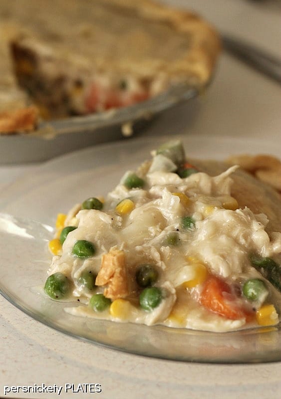 Homemade Easy Chicken Pot Pie is my idea of comfort food! Tender chicken, vegetables, and gravy, baked into a flaky pastry crust. This easy chicken pot pie recipe is a great use for turkey leftovers, too! Plate of semi-homemade easy Chicken Pot Pie