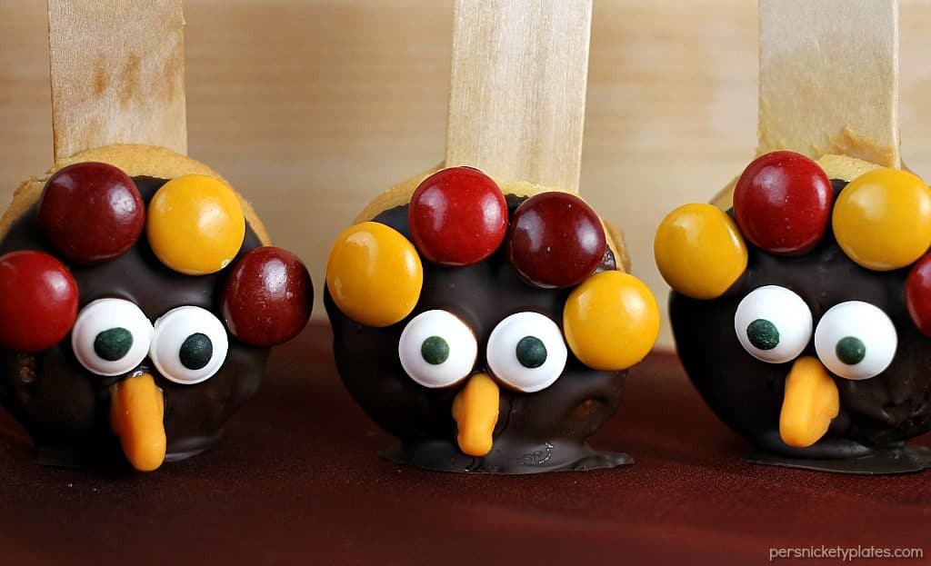 Nilla Wafer Thanksgiving Turkeys are cookies sandwiched together with peanut butter, dipped in chocolate, and decorated with fall colored M&Ms, candy corn, and candy eyes, all on a popsicle stick! So fun for the kids and festive for the Thanksgiving table!