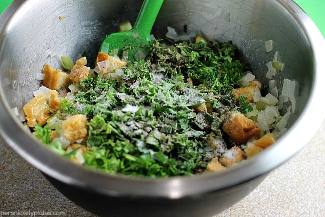Traditional Herb Stuffing is very easy to make and filled with fresh, flavorful herbs. It'll be a hit on any Thanksgiving table! | www.persnicketyplates.com #thanksgiving #stuffing #herbstuffing #easyrecipe #sidedish herbs and bread in mixing bowl