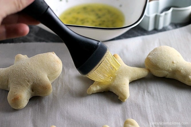 a pastry brush brushing butter onto dinner rolls