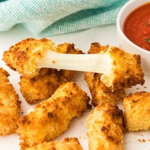 pile of mozzarella cheese sticks with the cheese being pulled apart from a broken one.
