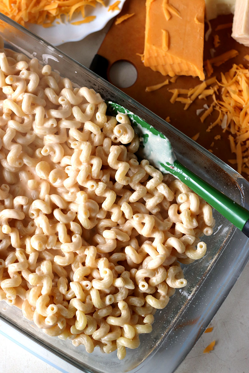 Homemade Baked Macaroni and Cheese is a delicious, super rich, five cheese baked mac and cheese recipe. This copycat steakhouse recipe is fancy enough to serve to guests for holidays, but so delicious, you'll want to make this easy baked mac and cheese recipe every day! www.persnicketyplates.com noodles and cheese in baking dish for best baked mac n cheese