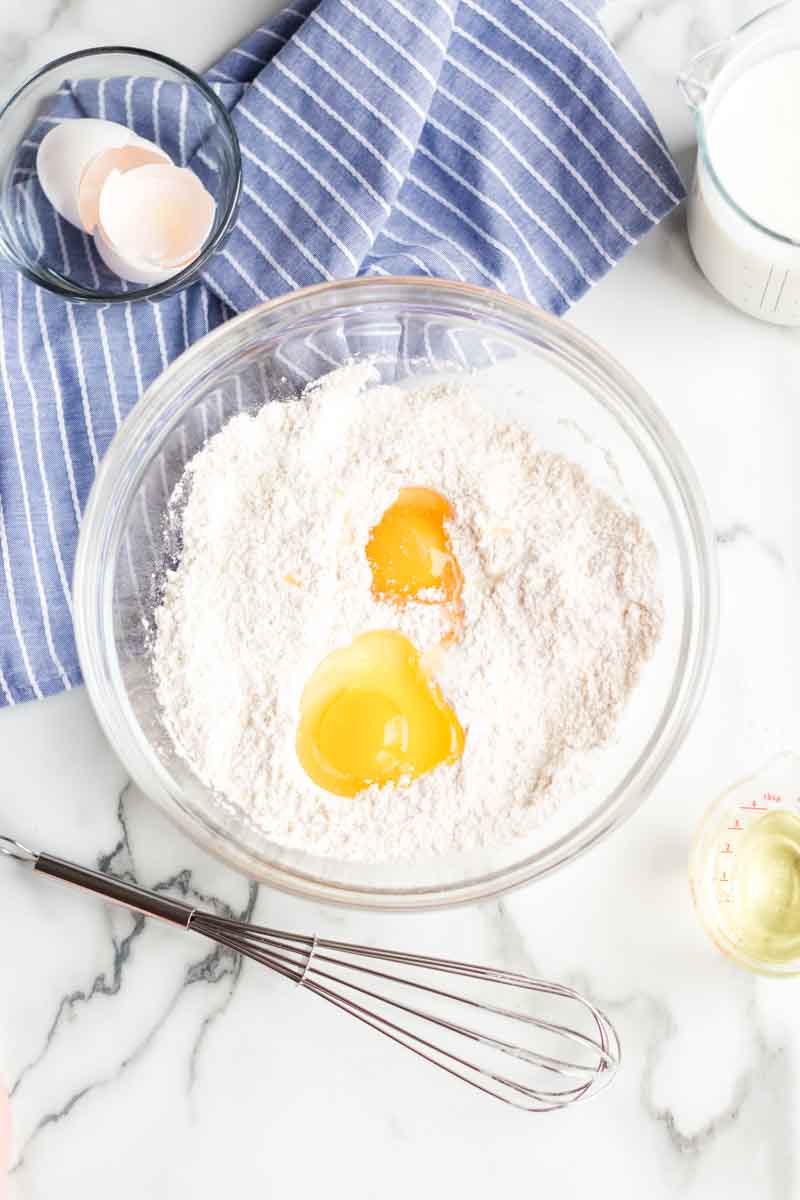 Buttermilk waffles are so easy to make from scratch - all you need is one bowl, a whisk, and a few everyday ingredients. Ditch the mix and give these homemade waffles a try! | www.persnicketyplates.com mixing bowl with flour, eggs, whisk