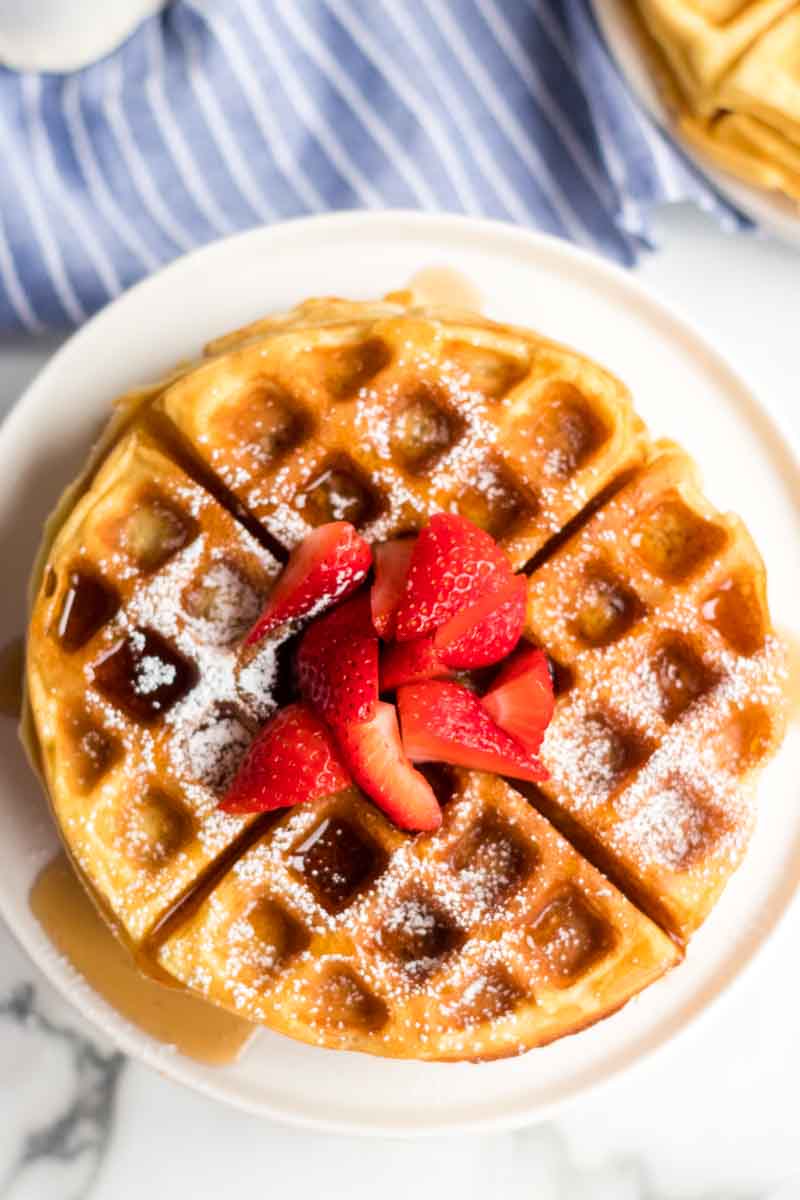 Buttermilk waffles are so easy to make from scratch - all you need is one bowl, a whisk, and a few everyday ingredients. Ditch the mix and give these homemade waffles a try! | www.persnicketyplates.com stack of waffles with syrup, powdered sugar, and strawberries