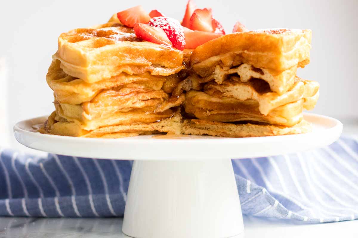 Buttermilk waffles are so easy to make from scratch - all you need is one bowl, a whisk, and a few everyday ingredients. Ditch the mix and give these homemade waffles a try! | www.persnicketyplates.com stack of 6 buttermilk waffles cut into with syrup and strawberries
