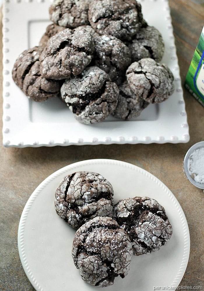 Chocolate Gooey Butter Cookies are light and pillowy and melt in your mouth! At only six ingredients, they just might be your new favorite cookie! | www.persnicketyplates.com #dessert #cookies #cakemixcookies #chocolate #baking #easyrecipe #semihomemade #christmascookies white platters of christmas gooey butter cookies