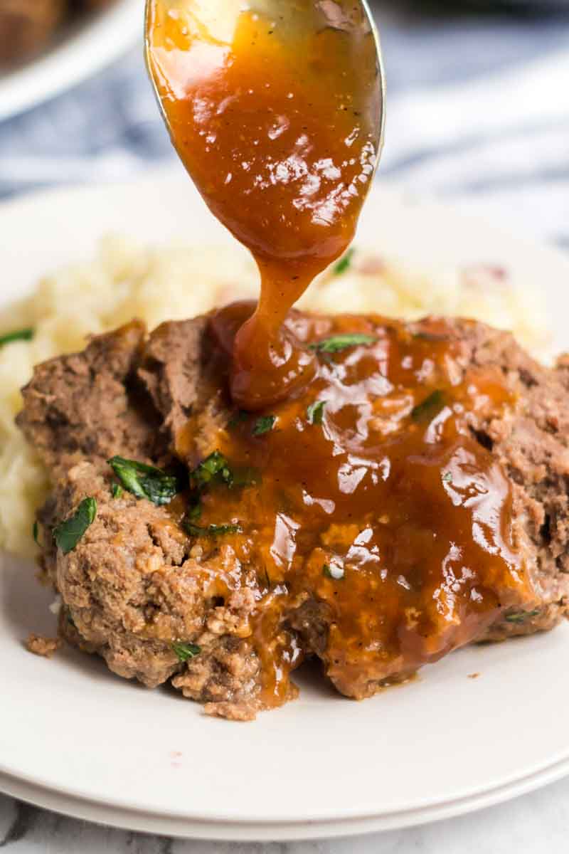 slice of meatloaf with brown gravy being spooned over top 