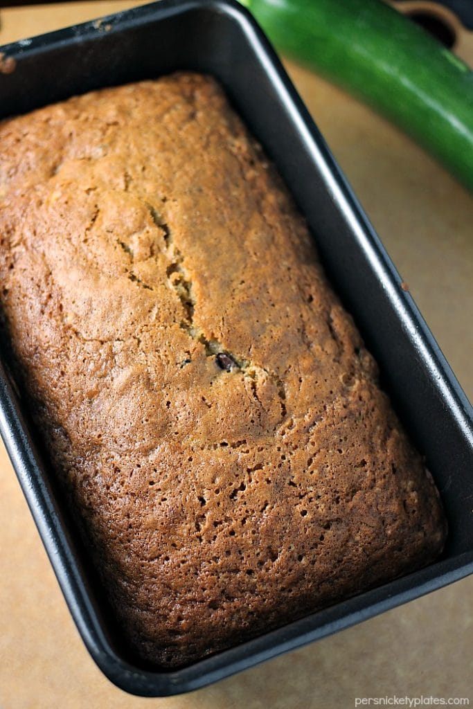 I've been making this Paula Deen Zucchini Bread recipe for years because it really is the best zucchini bread! It's easy to prepare and it makes two loaves so you can share. | www.persnicketyplates.com #zucchinibread #quickbread #dessert #zucchini #chocolatechips overhead shot of a loaf of zucchini bread in loaf pan.