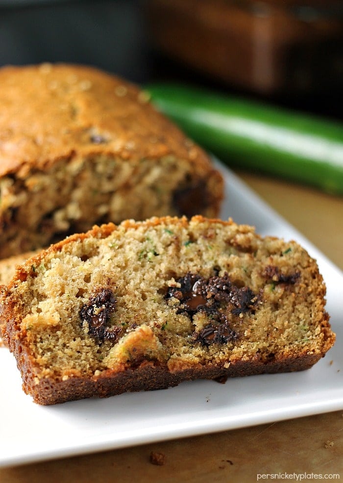 I've been making this Paula Deen Zucchini Bread recipe for years because it really is the best zucchini bread! It's easy to prepare and it makes two loaves so you can share. | www.persnicketyplates.com #zucchinibread #quickbread #dessert #zucchini #chocolatechips white platter of sliced zucchini bread
