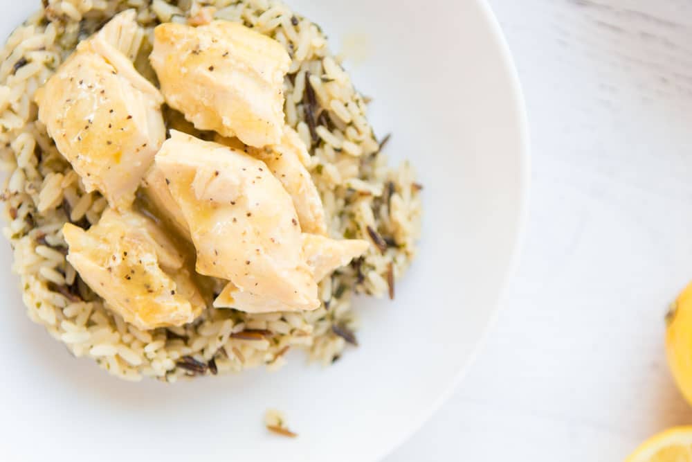 This Crock Pot Lemon Chicken is so easy and perfect for a busy weeknight. This 4 ingredient, quick chicken dinner is amazingly flavorful and sure to be your new favorite meal. Serve with vegetables and ready to serve rice for a fast healthy dinner! | www.persnicketyplates.com overhead shot of chicken on wild rice in a white bowl