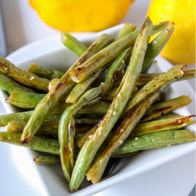 Oven roasted garlic green beans are a super simple and healthy side dish that I can never stop eating! Only five ingredients in this side dish that pairs well with just about anything. | www.persnicketyplates.com white bowl of oven roasted garlic green beans