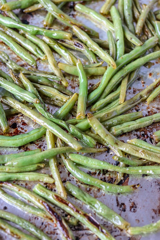 Oven roasted garlic green beans are a super simple and healthy side dish that I can never stop eating! Only five ingredients in this side dish that pairs well with just about anything. | www.persnicketyplates.com oven roasted garlic green beans on baking sheet