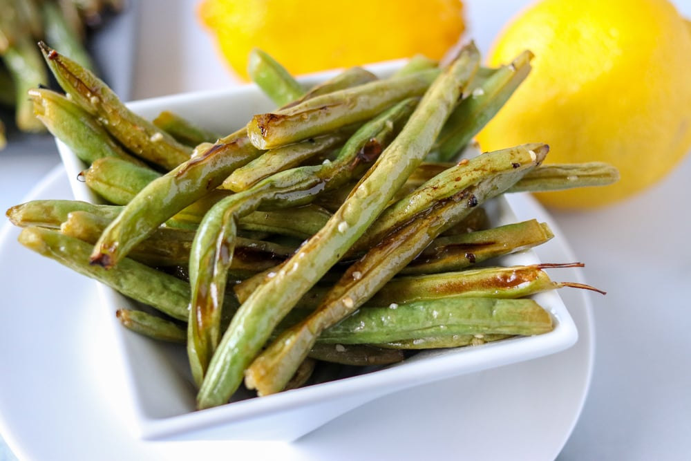 Oven roasted garlic green beans are a super simple and healthy side dish that I can never stop eating! Only five ingredients in this side dish that pairs well with just about anything. | www.persnicketyplates.com oven roasted garlic green beans in white plate