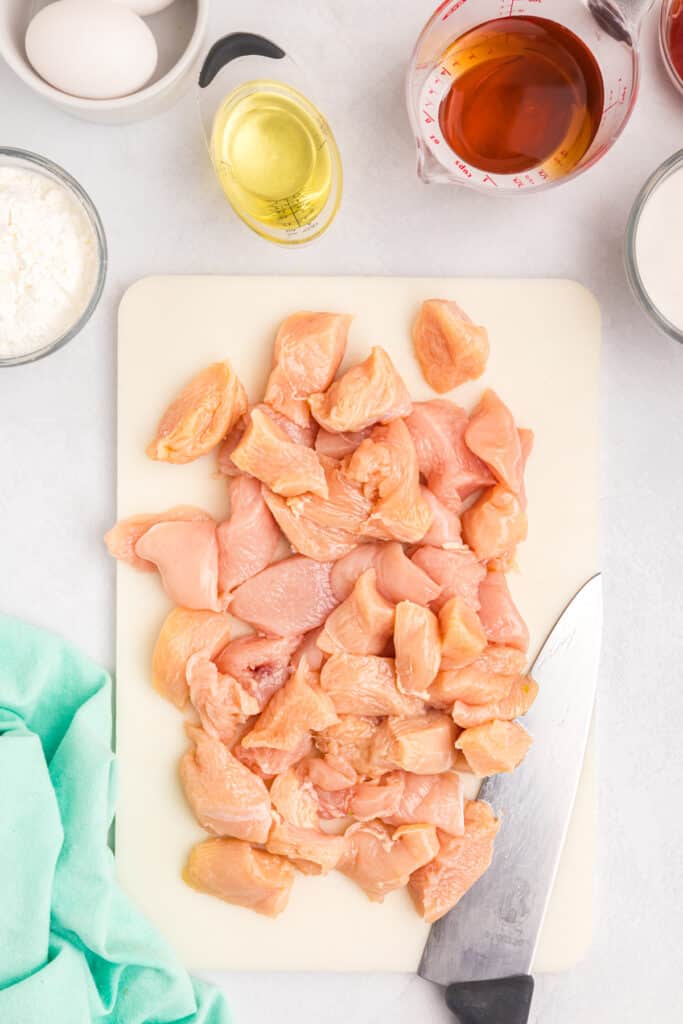 overhead shot of cubed raw chicken on a cutting board.