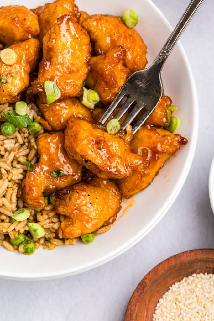 fork poking into a chunk of sweet & sour chicken.