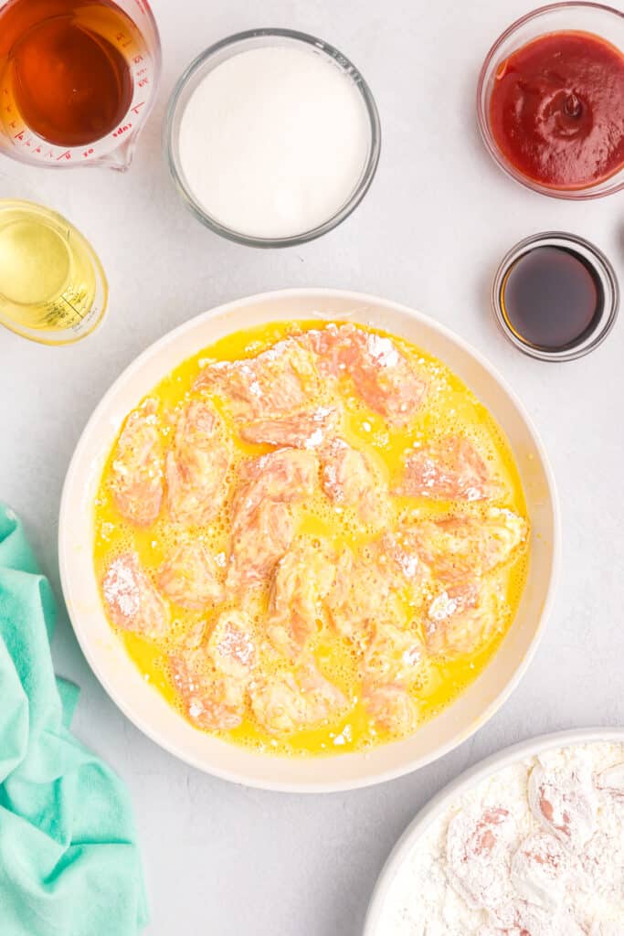 chicken pieces in a bowl of egg wash.