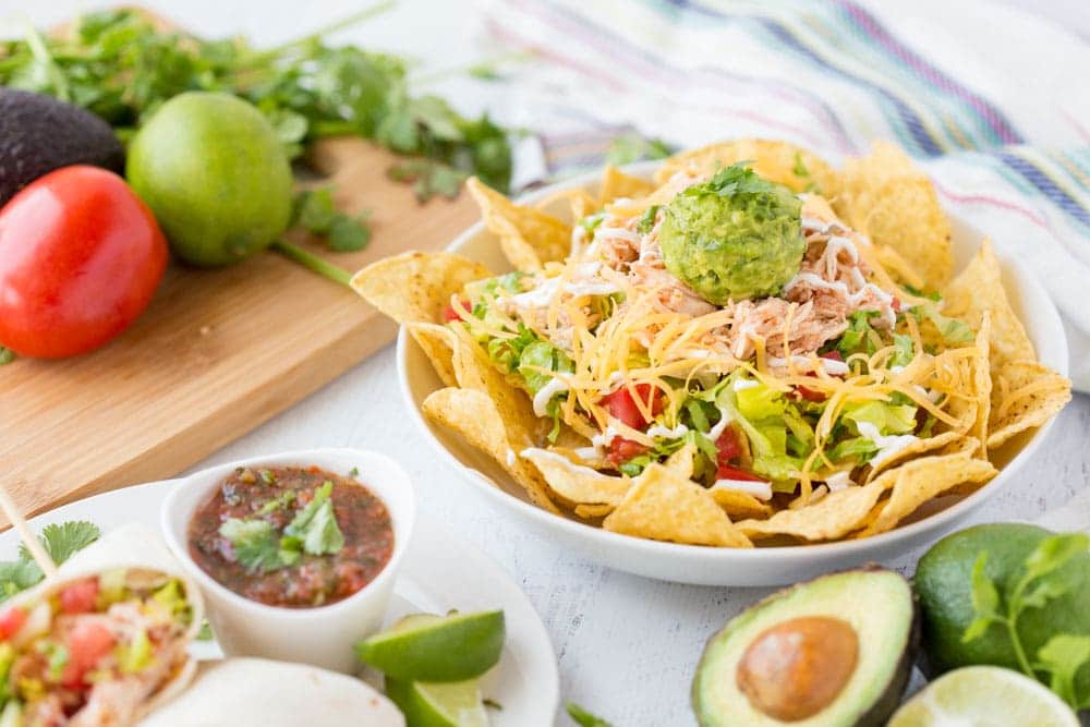 bowl of nachos with crockpot salsa chicken Three ingredient Crock Pot Salsa Chicken is in my regular dinner rotation because it's so easy & so good! Flavorful and versatile, this crockpot chicken breast recipe can be made into burritos, taco bowls, nachos, whatever you feel like! | www.persnicketyplates.com