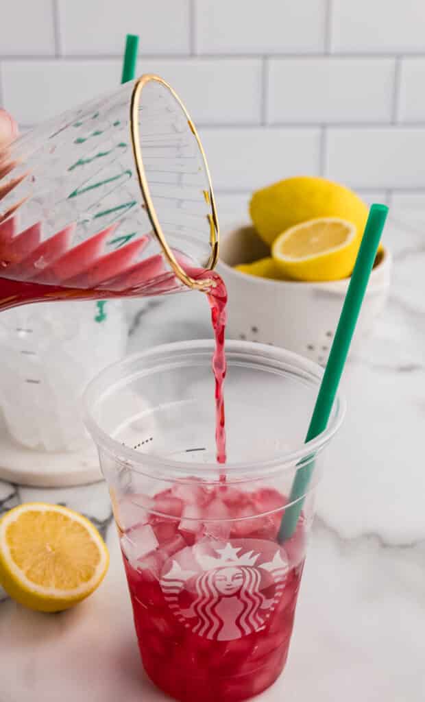 pink passion tea pouring into a cup of ice.