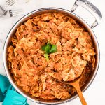 overhead shot of bow tie pasta lasagna skillet with a spoon.