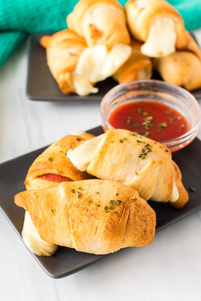 pizza rolls on a plate next to marinara dipping sauce.