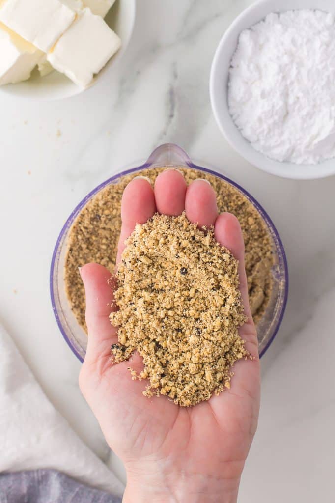 hand holding cookie crumbs that look like sand.