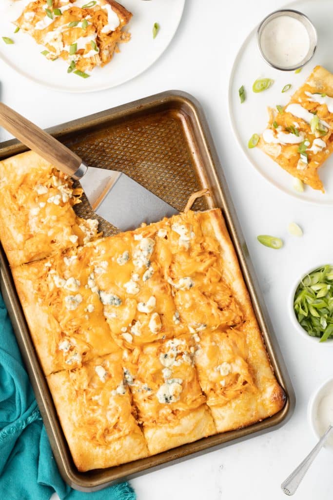 overhead shot of sheet pan buffalo chicken pizza with a slice missing.