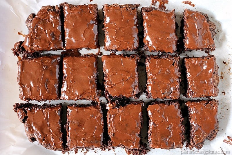 overhead shot of frosted brownies sliced on parchment paper.