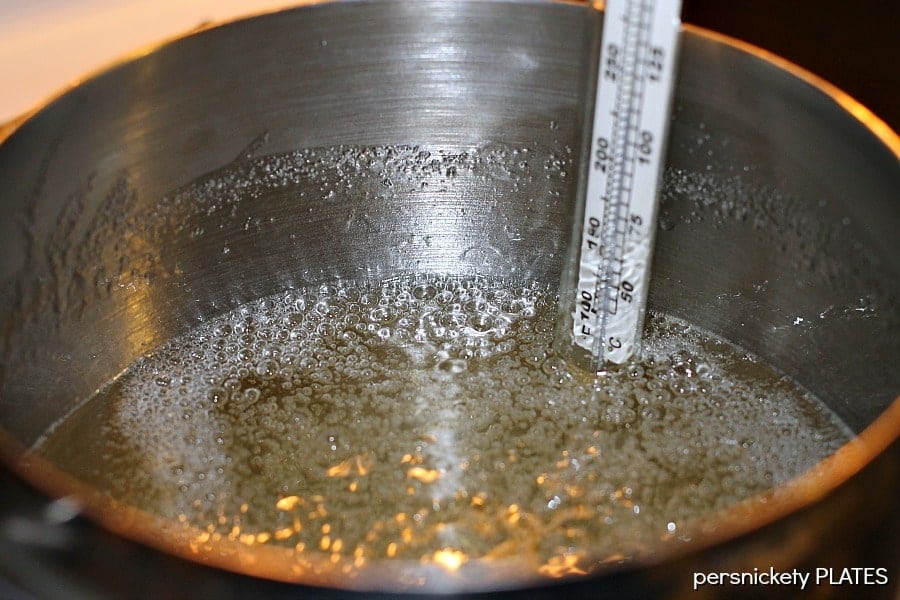 Homemade Hard Candy is easy to make and really easy to customize to whatever flavor and color you want! This hard candy recipe will become a favorite in your family. | www.persnicketyplates.com #hardcandy #candy #christmascandy #christmas sugar boiling in a pot with a candy thermometer
