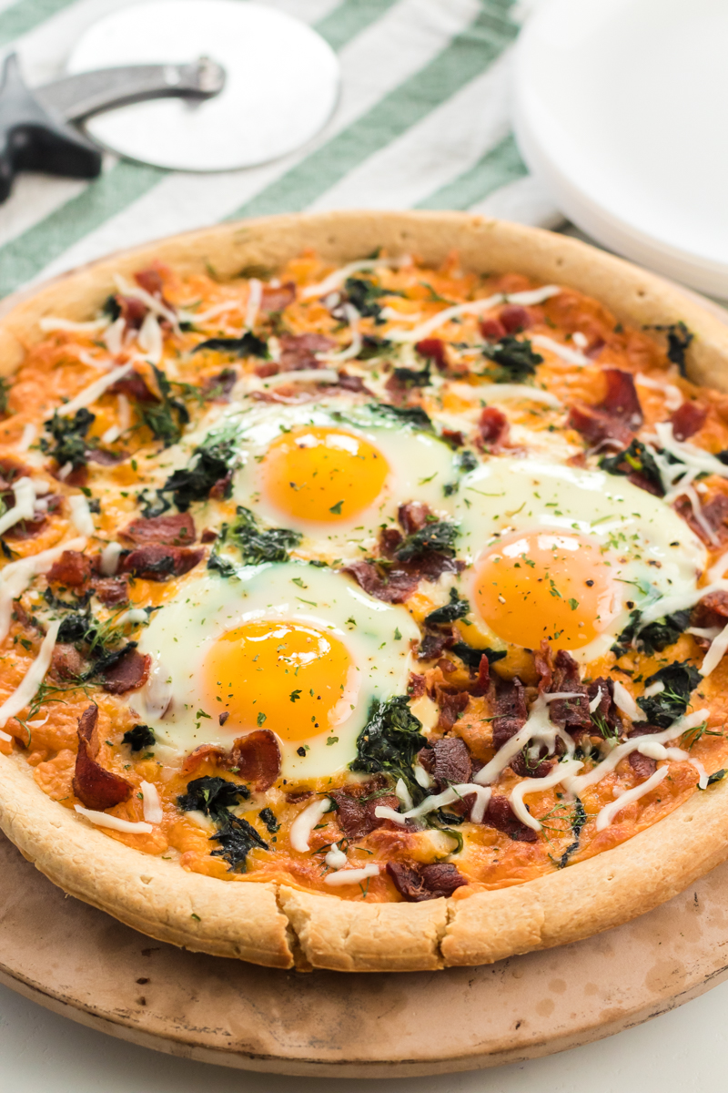 Bacon & spinach breakfast pizza is a filling and unique way to start your day. Pizza for breakfast is always a good idea! | www.persnicketyplates.com #pizza #breakfast #breakfastpizza #easyrecipe breakfast pizza topped with cooked eggs