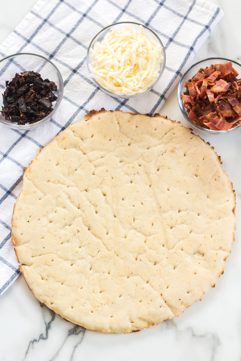 This BLT Pizza is semi-homemade and topped with cheese, bacon, lettuce, and tomatoes then drizzled with ranch dressing - a super easy meal for pizza night at home! | www.persnicketyplates.com pizza crust, sun dried tomatoes, mozzarella cheese, and chopped bacon for blt pizza