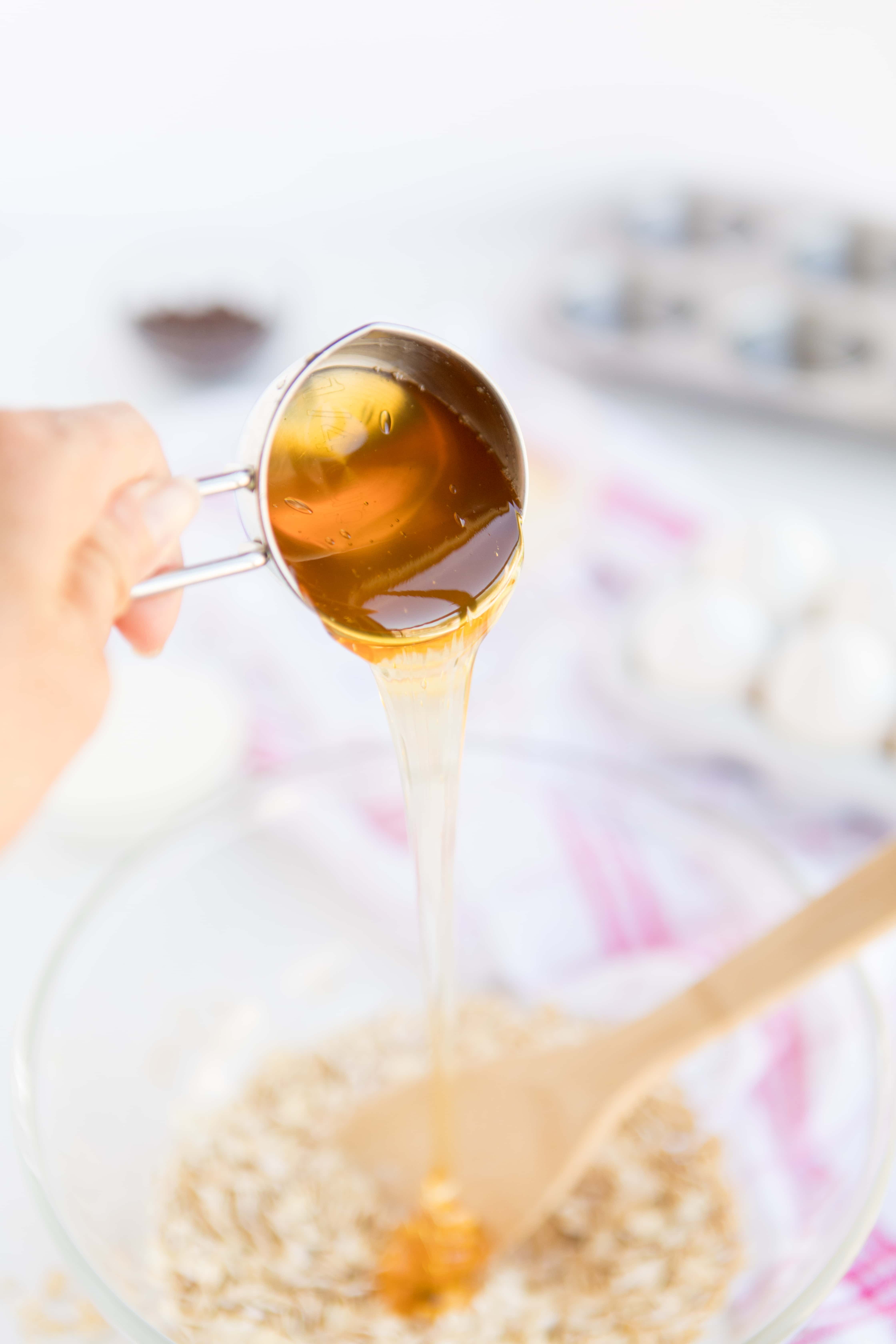 pouring honey from a measuring cup inot a bowl to make Baked Oatmeal Breakfast Cups