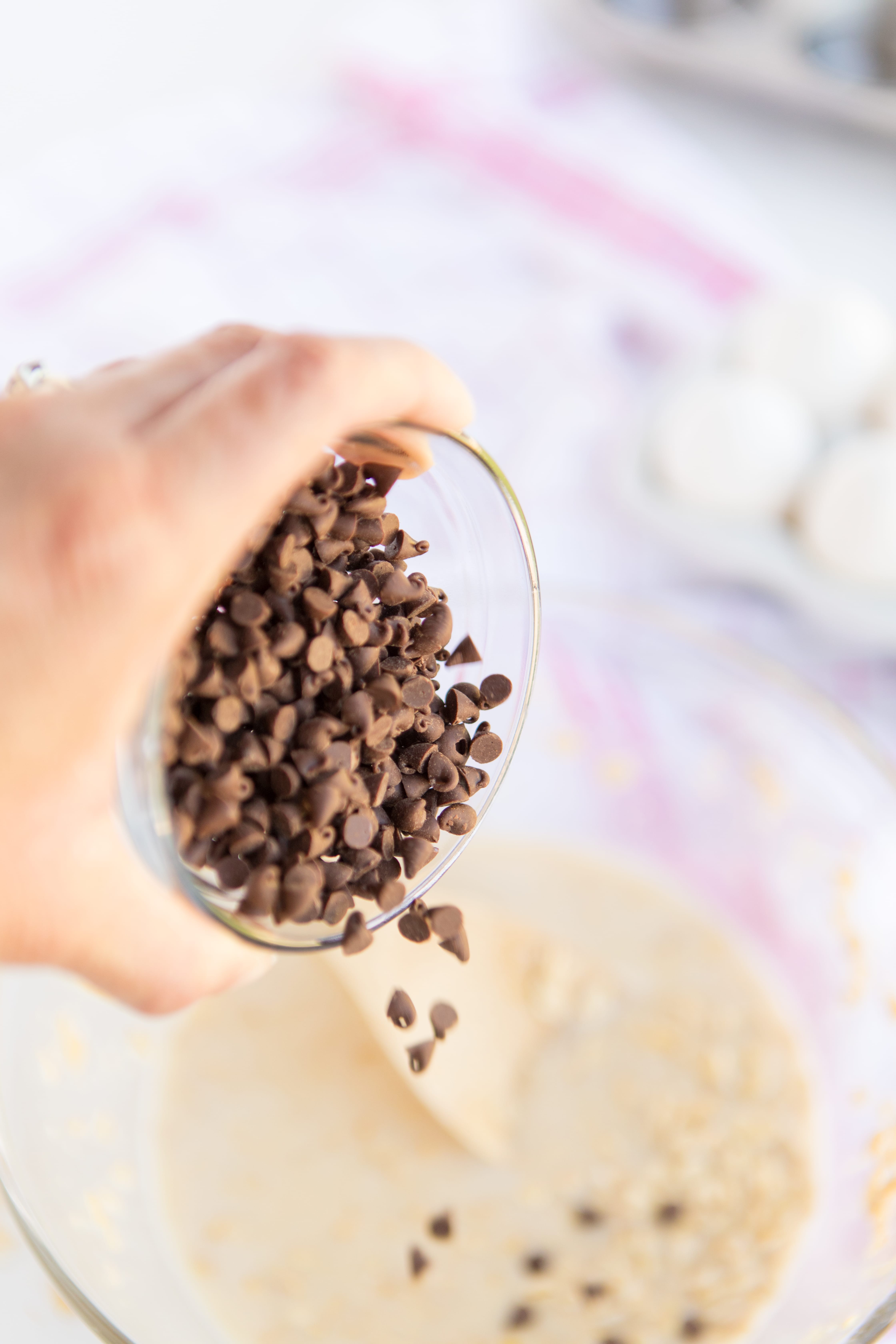 pouring mini chocolate chips into Baked Oatmeal Breakfast Cups batter