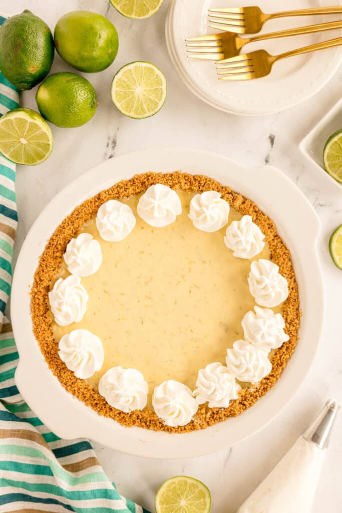 overhead shot of a key lime pie topped with dollops of whipped cream.