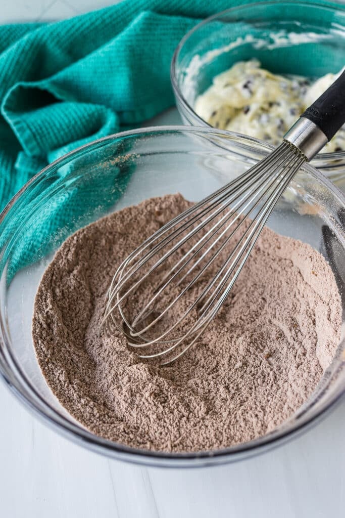 A bowl of sifted dry chocolate ingredients with a whisk inside.