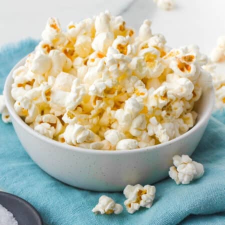 white bowl of popcorn on a teal napkin.