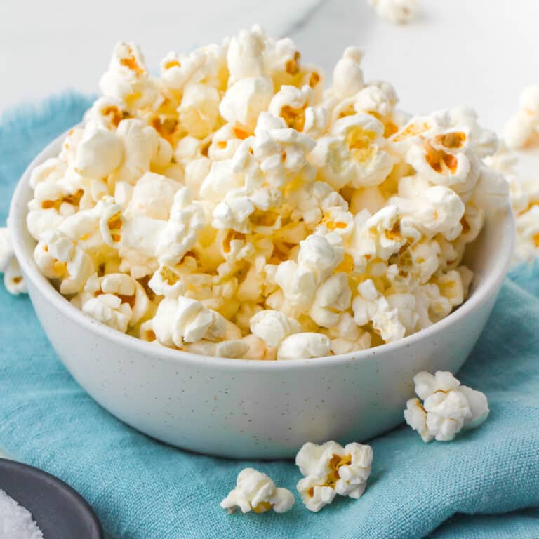 white bowl of popcorn on a teal napkin.