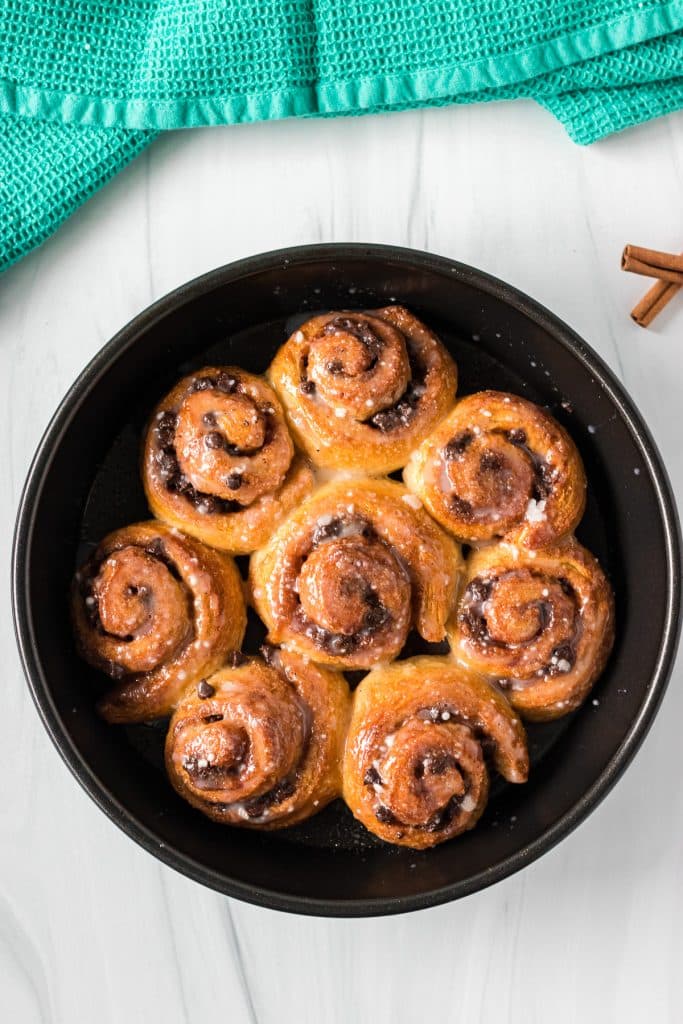 overhead shot of glazed cinnamon rolls in a round baking dish.