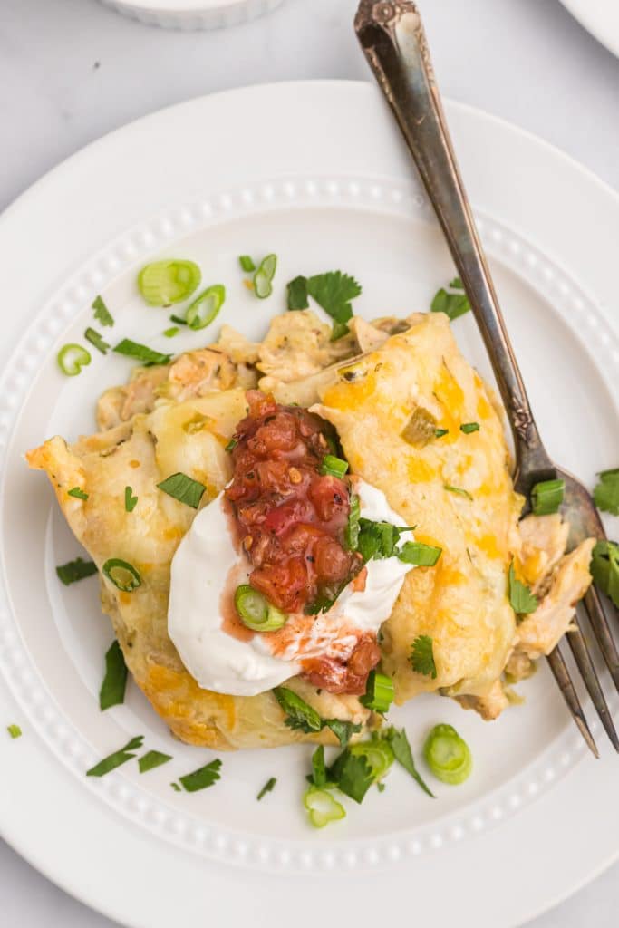 overhead shot of an enchilada topped with sour cream, salsa, and cilantro.