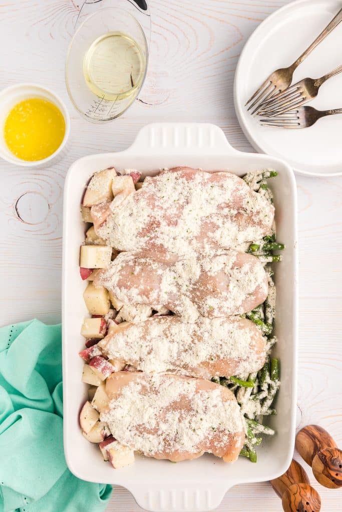 overhead shot of seasoning sprinkled in chicken in a baking dish.