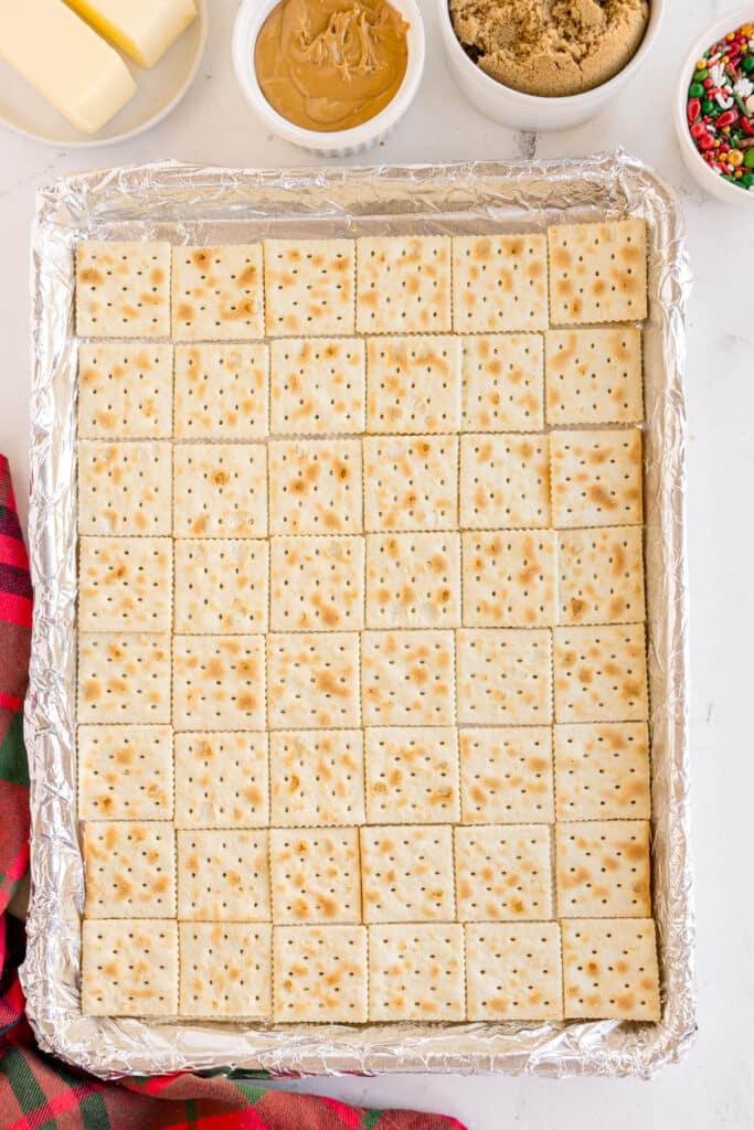 A baking tray lined with saltine crackers on foil.