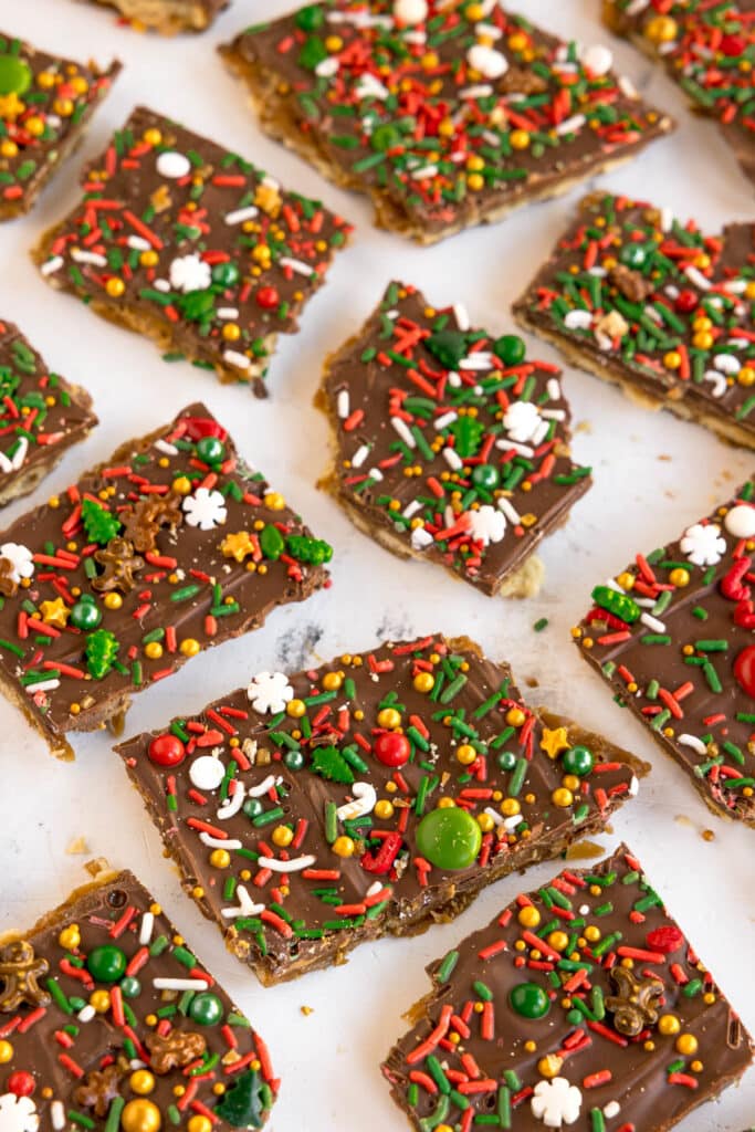 Pieces of chocolate-covered Christmas crack decorated with colorful holiday sprinkles.