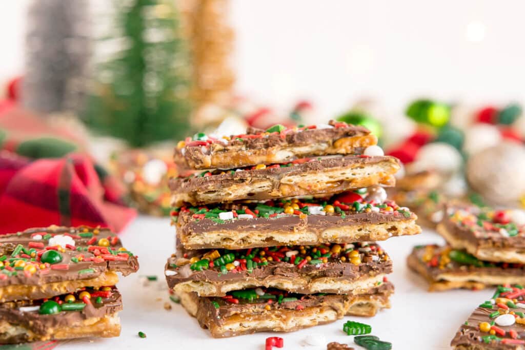 A stack of festive chocolate-covered Christmas crack topped with colorful sprinkles.
