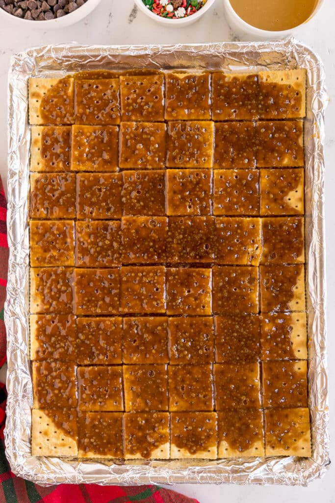 toffee poured over saltine crackers in a baking sheet lined with foil.