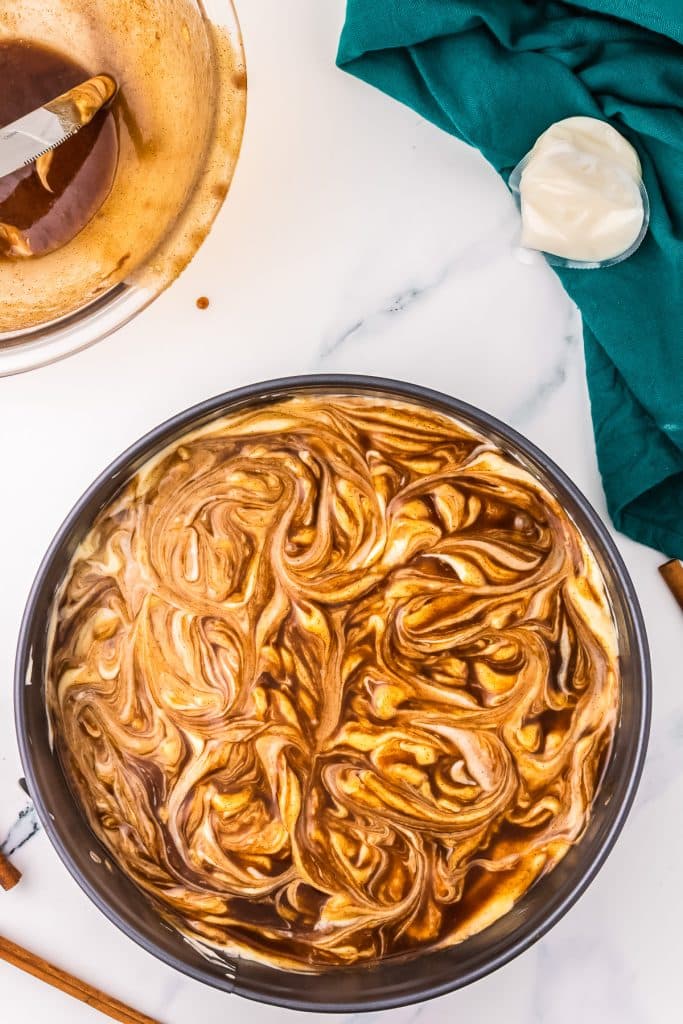 springform pan with cinnamon swirls in cheesecake batter.