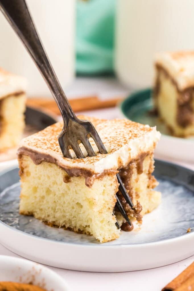 fork poking into a slice of cinnamon roll cake.