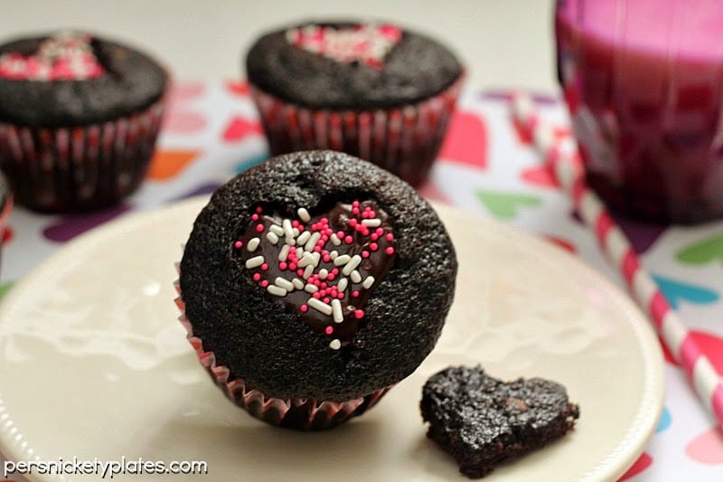 Dark chocolate cupcakes with a heart shaped cut-out filled with chocolate ganache and topped with sprinkles. Perfect for Valentine's Day!