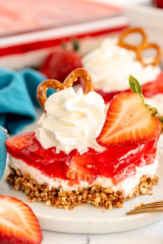 slice of layered strawberry pretzel dessert with a bite missing.