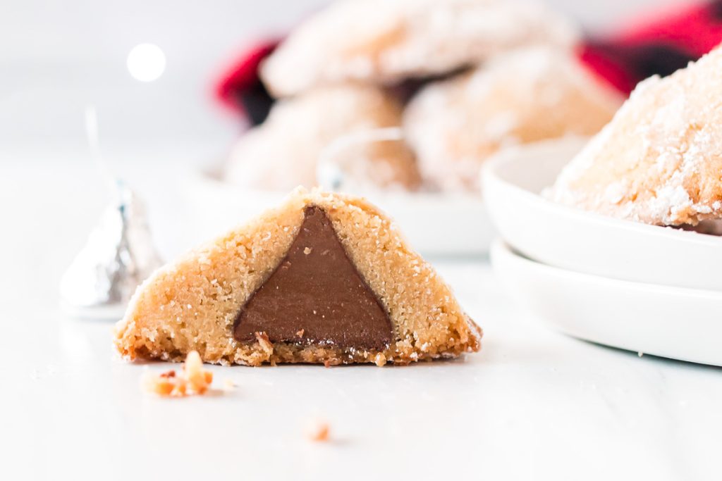 close up on a sugar cookie sliced in half showing a hershey's kiss inside