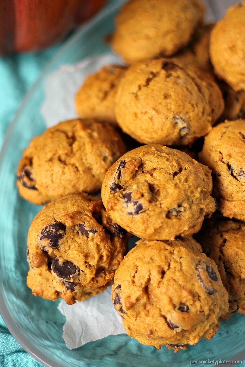 horizontal platter of pumpkin chocolate chip cookies on clear plate with a teal napkin