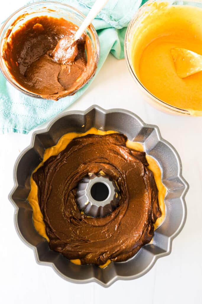 layered chocolate and pumpkin cake batter in a bundt pan.